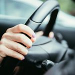 34953670 sports car steering wheel hands of a young girl with purple nail polish